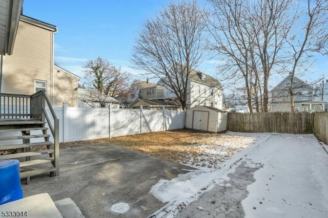 snowy yard featuring a patio area and a shed