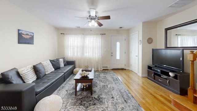 living room with a baseboard heating unit, wood-type flooring, and ceiling fan