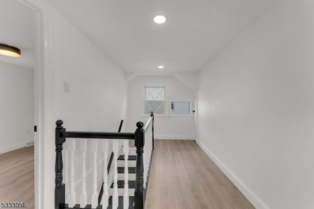 corridor with lofted ceiling and light hardwood / wood-style floors