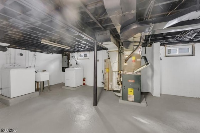 basement featuring electric panel, washing machine and dryer, heating unit, and gas water heater