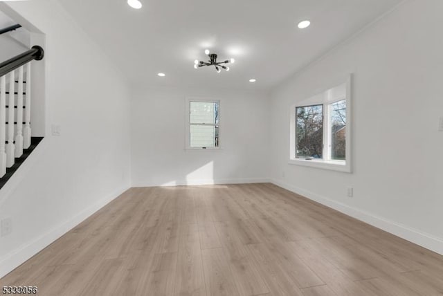 spare room featuring light wood-type flooring, a chandelier, and a healthy amount of sunlight