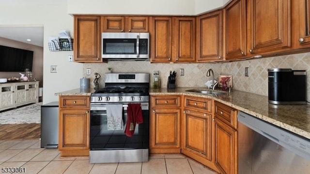 kitchen featuring stainless steel appliances, light tile patterned flooring, sink, and light stone counters