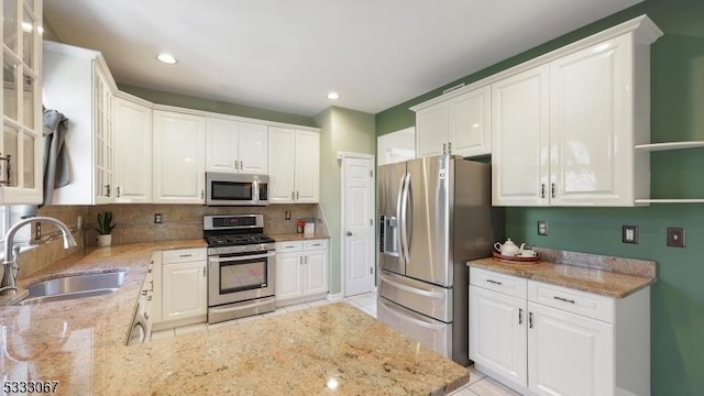 kitchen with light stone countertops, sink, white cabinets, and appliances with stainless steel finishes