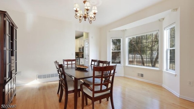 dining area featuring light wood-type flooring and a chandelier