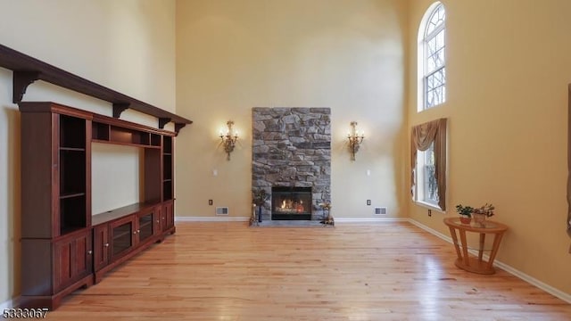 living room featuring a high ceiling, light hardwood / wood-style flooring, and a fireplace