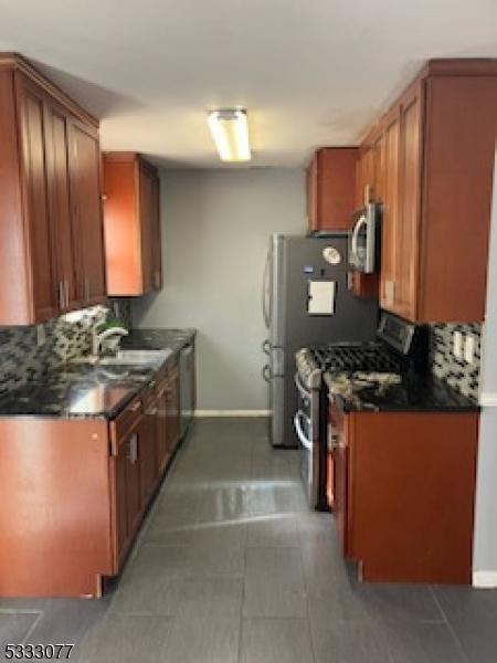 kitchen featuring stainless steel appliances, baseboards, a sink, and dark countertops
