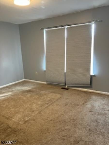 carpeted spare room featuring baseboards