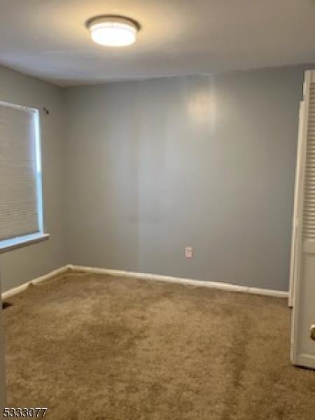unfurnished room featuring carpet flooring and baseboards