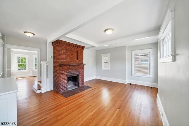 unfurnished living room with a brick fireplace and light hardwood / wood-style floors