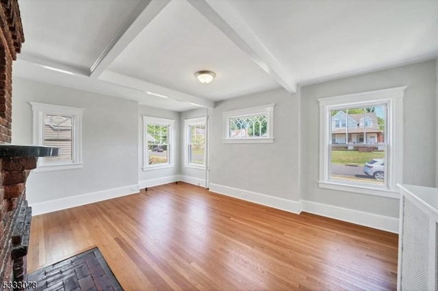 unfurnished living room with beam ceiling, a brick fireplace, and hardwood / wood-style flooring