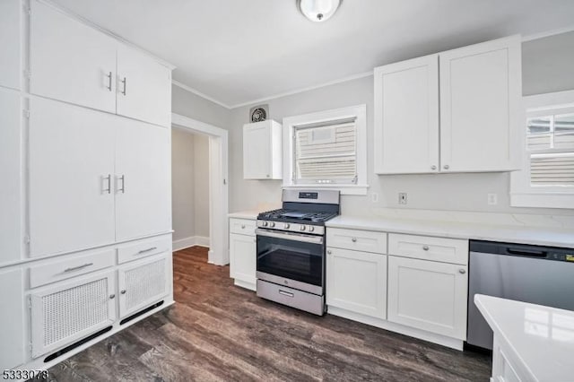 kitchen with appliances with stainless steel finishes, dark hardwood / wood-style flooring, crown molding, and white cabinetry