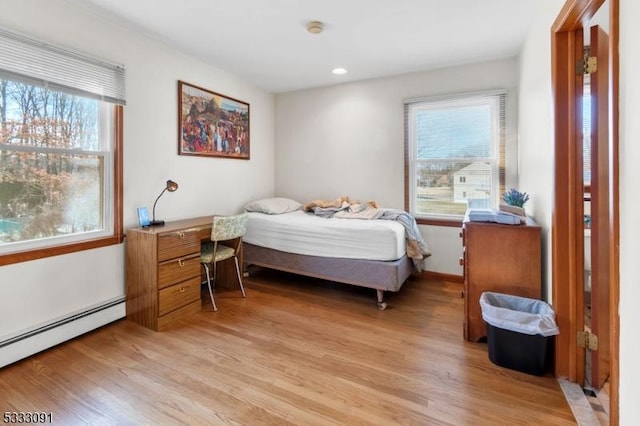 bedroom with light hardwood / wood-style floors and a baseboard radiator