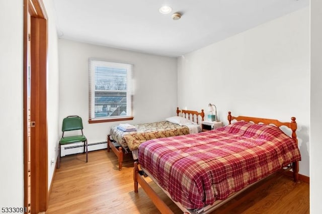 bedroom with a baseboard heating unit and hardwood / wood-style floors