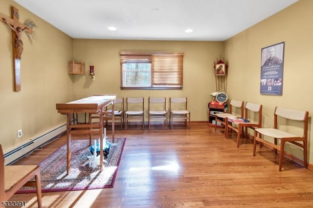 interior space with a baseboard heating unit and light hardwood / wood-style floors