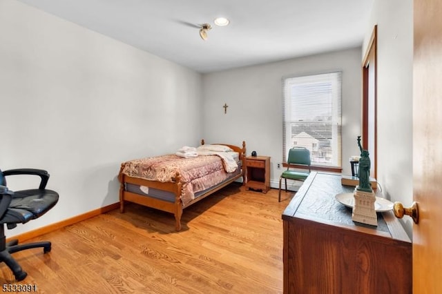 bedroom with light wood-type flooring and a baseboard heating unit