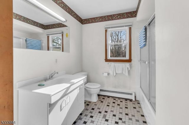 full bathroom featuring toilet, vanity, a baseboard heating unit, and bath / shower combo with glass door