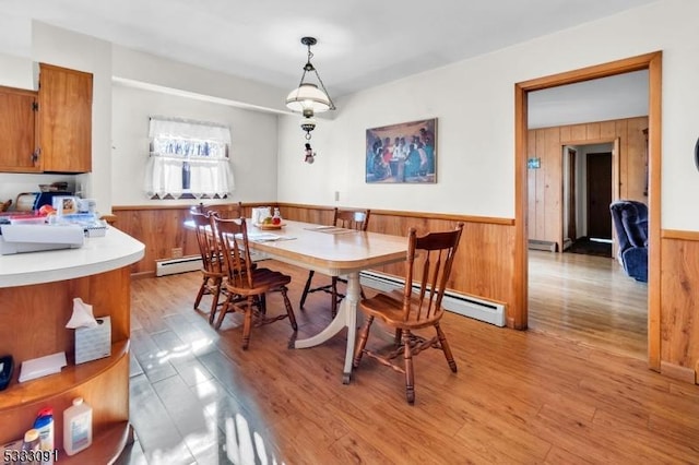 dining room with light hardwood / wood-style floors, wooden walls, and a baseboard radiator