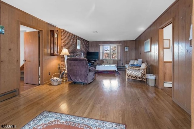 living room with wood walls, wood-type flooring, and a baseboard radiator