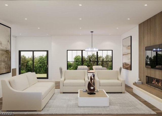 living area featuring recessed lighting, a healthy amount of sunlight, a glass covered fireplace, and a notable chandelier