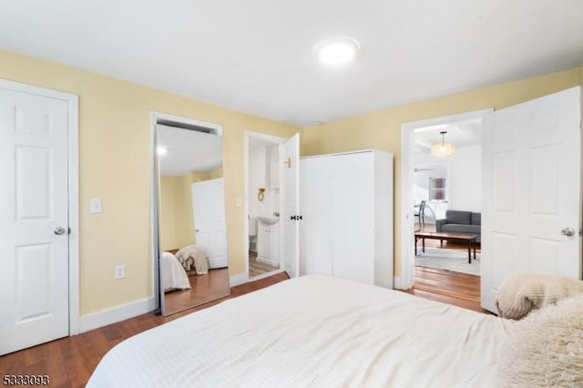 bedroom with connected bathroom and dark hardwood / wood-style floors