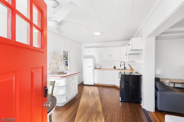 kitchen featuring butcher block countertops, sink, white cabinetry, dark wood-type flooring, and white refrigerator