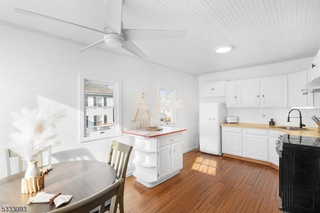 kitchen with ceiling fan, sink, hardwood / wood-style flooring, range with electric cooktop, and white cabinets