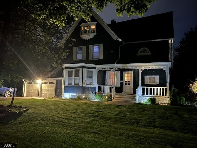 view of front of property featuring covered porch, a garage, and a lawn