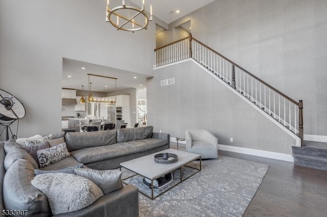 living room featuring hardwood / wood-style floors, a chandelier, and a towering ceiling