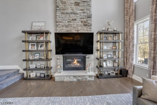 unfurnished living room with hardwood / wood-style floors and a stone fireplace