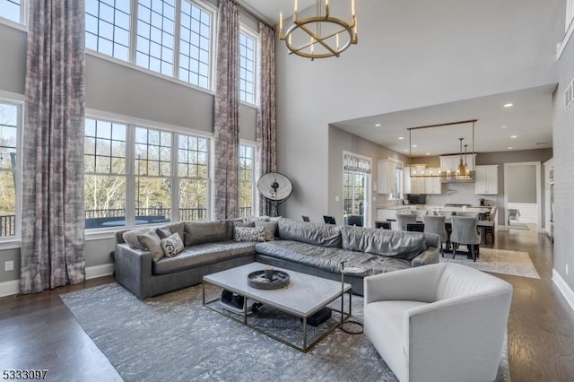 living room with a towering ceiling, an inviting chandelier, and dark hardwood / wood-style floors