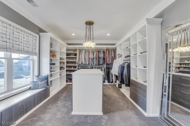 walk in closet with a notable chandelier and dark carpet