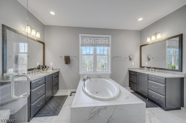 bathroom featuring a relaxing tiled tub and vanity