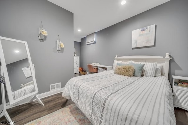 bedroom featuring hardwood / wood-style floors and an AC wall unit