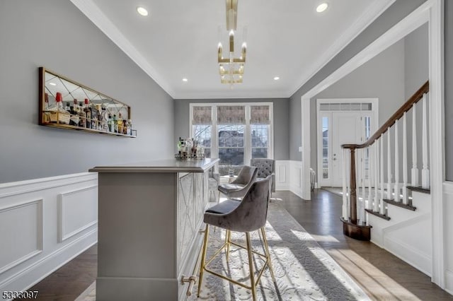 dining area featuring an inviting chandelier, dark hardwood / wood-style floors, bar area, and ornamental molding