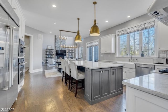 kitchen with light stone countertops, white cabinets, stainless steel appliances, and a kitchen island