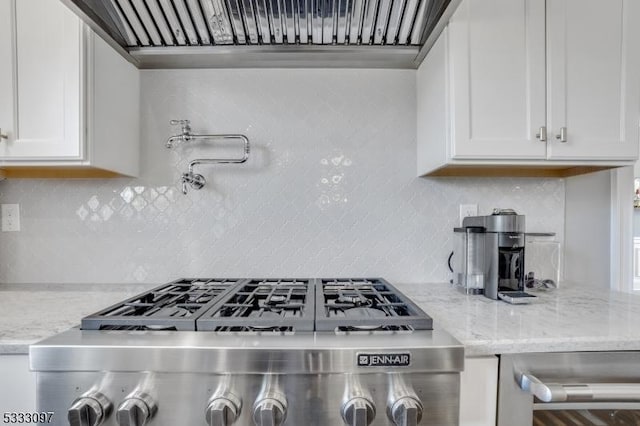 kitchen with light stone counters, white cabinets, range, and tasteful backsplash