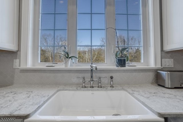 details with sink, white cabinetry, light stone counters, and decorative backsplash