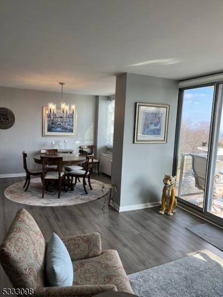 living room featuring floor to ceiling windows, wood-type flooring, and an inviting chandelier