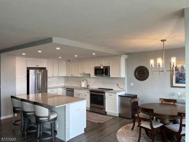 kitchen with white cabinets, decorative light fixtures, stainless steel appliances, dark hardwood / wood-style floors, and a chandelier