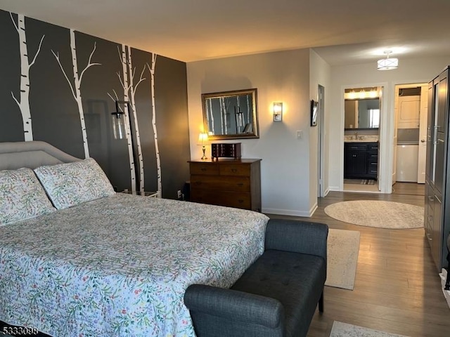 bedroom featuring refrigerator, sink, connected bathroom, and hardwood / wood-style floors