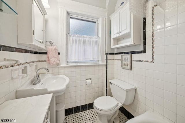 bathroom featuring tile walls, tile patterned flooring, a bathing tub, and toilet