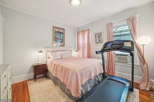 bedroom with cooling unit and light hardwood / wood-style floors