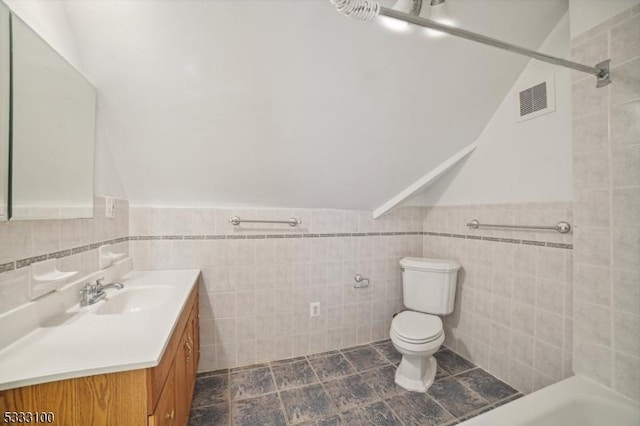 bathroom featuring vanity, a bathing tub, tile walls, and toilet