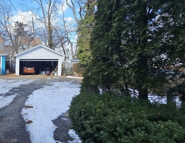 snowy yard with a garage and an outdoor structure