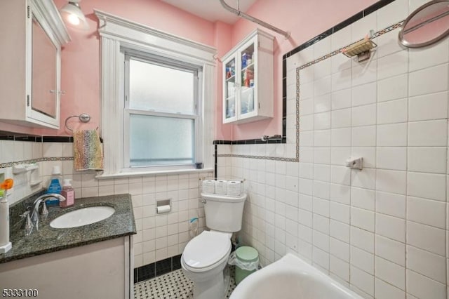 bathroom featuring toilet, tile walls, vanity, a bathtub, and tile patterned flooring