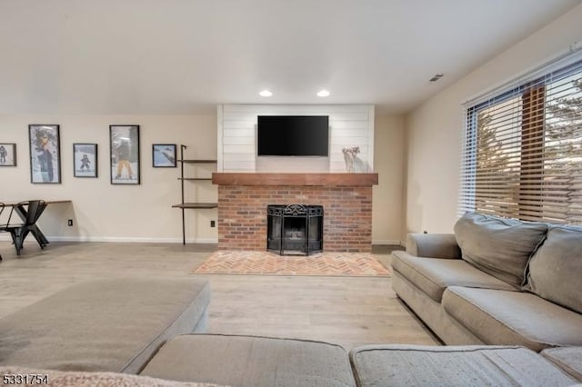 living room with a brick fireplace and light hardwood / wood-style flooring