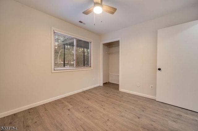 unfurnished bedroom featuring ceiling fan, light hardwood / wood-style floors, and a closet