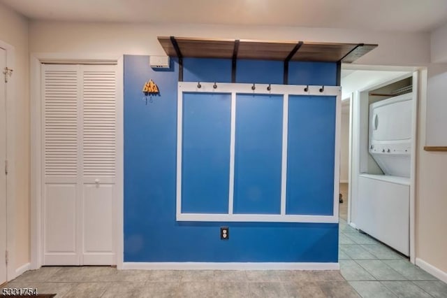 mudroom featuring stacked washing maching and dryer and tile patterned floors