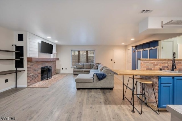 living room with a fireplace, sink, and light hardwood / wood-style flooring