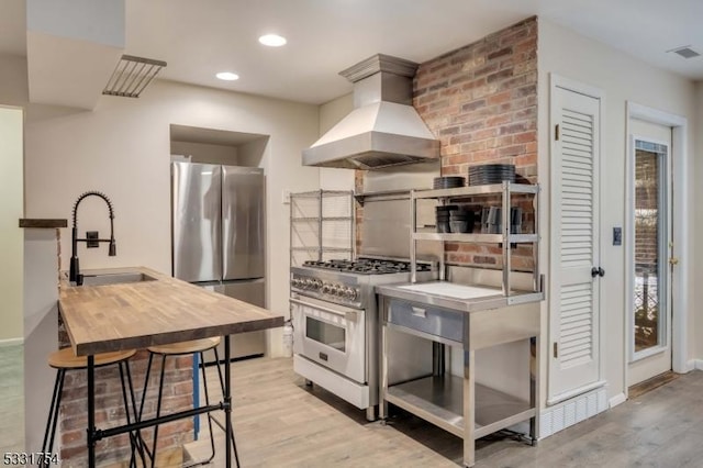 kitchen featuring light hardwood / wood-style flooring, appliances with stainless steel finishes, sink, and custom range hood